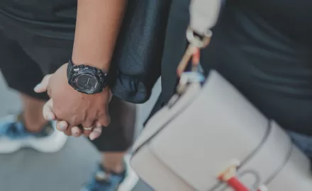 Casal de mãos dadas usando relógios masculinos e femininos, representando estilo e elegância atemporais.